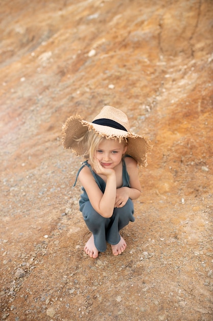 Little cute girl in stylish clothes on a background of rocks