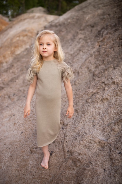 Little cute girl in stylish clothes on a background of rocks