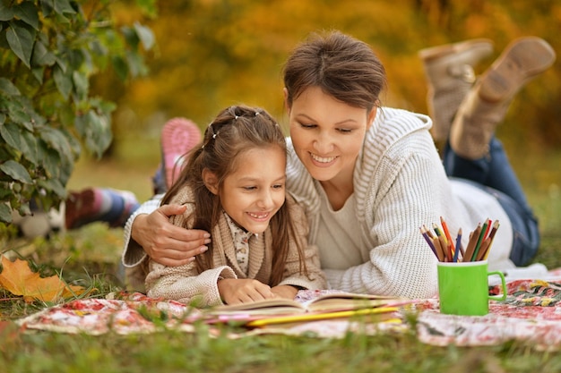 Little cute girl with her mother  reading book in  park