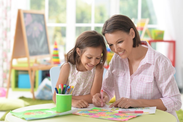 Little cute girl with mother drawing at home