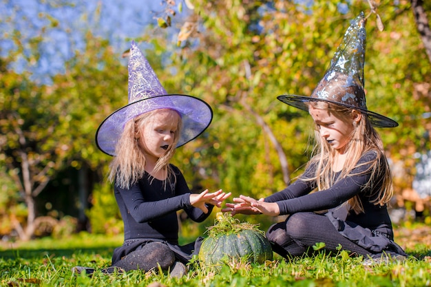 Little cute girls casting a spell on Halloween in witch costume