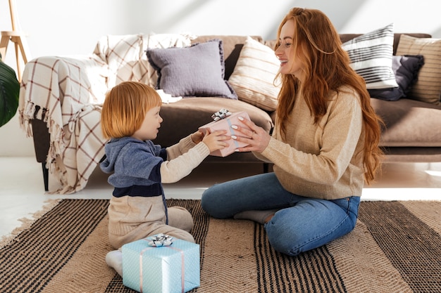 Little cute red haired boy gives mom a new year gift