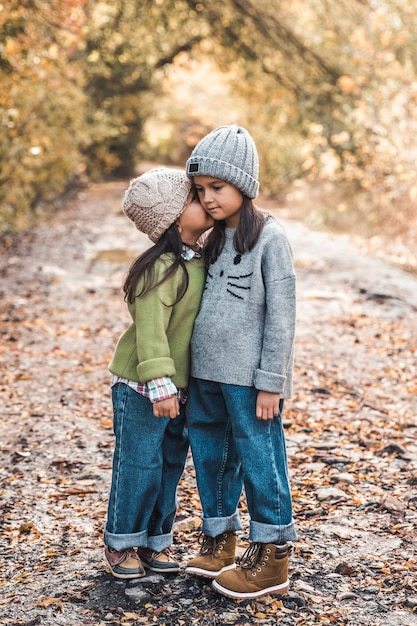 Little cute smiling girls walking together in autumn day. Friendship. Happy family concept