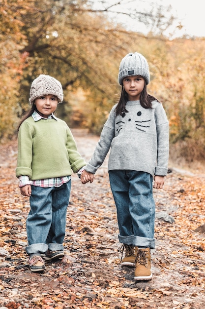 Little cute smiling girls walking together in autumn day