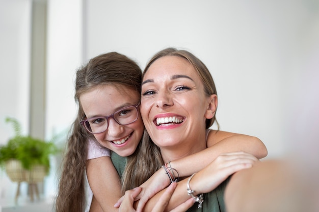 Little daughter young mother faces webcam close up view. Adorable kid girl use smartphone have fun with older sister making selfie photography, vloggers record new vlog, enjoy funny activity concept