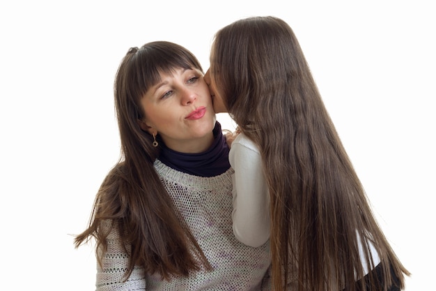 Little doughter kissing her mother at the cheek isolated on white background