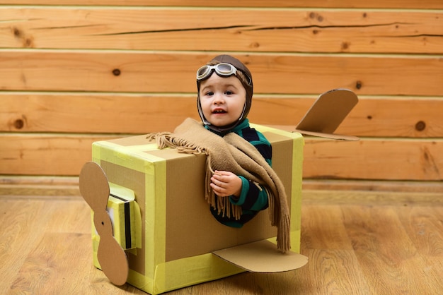 Little dreamer boy playing with a cardboard airplane