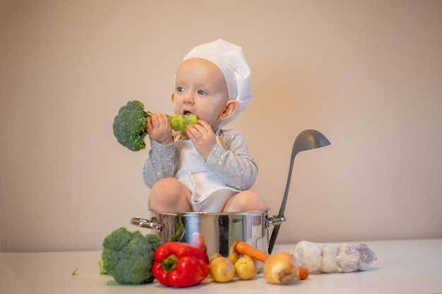 Little female chef preparing vegetable soup in kitchen