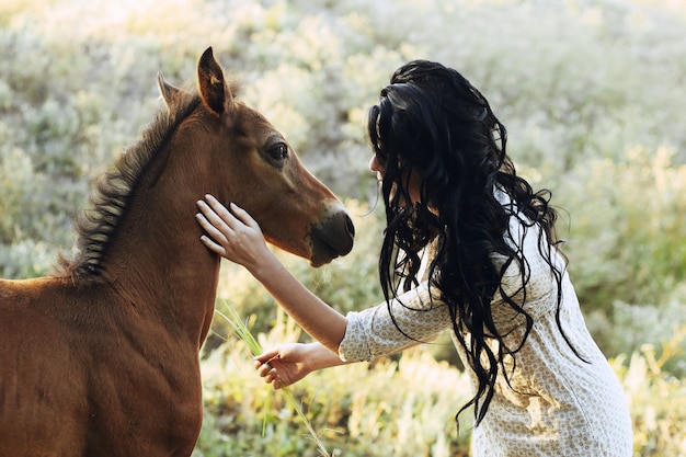 Little foal brown horse and girl outdoors