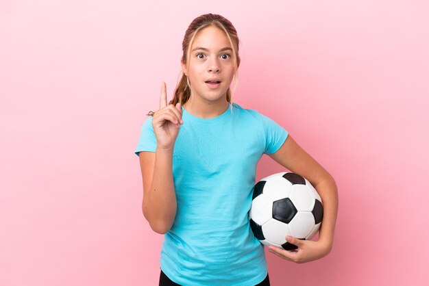 Little football player girl isolated on pink background thinking an idea pointing the finger up