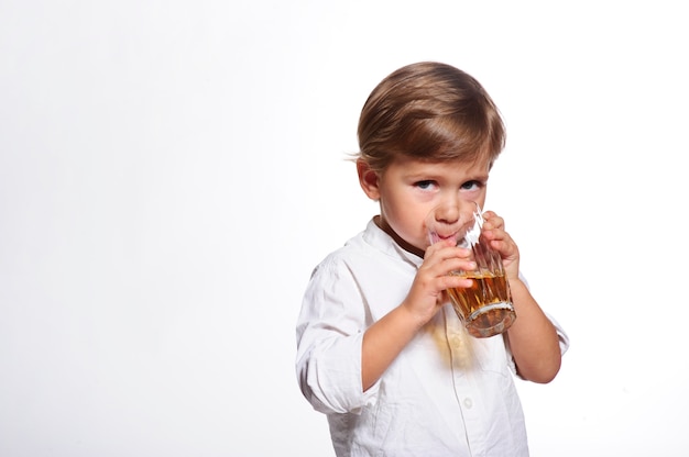 Little funny boy drinking a fresh juice