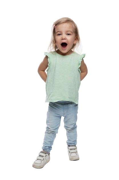 A little funny girl with an open mouth in jeans is standing Full height Isolated on white background Vertical