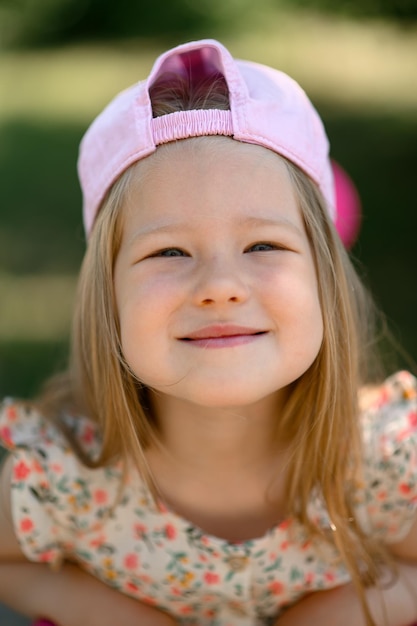 A little girl 3 years old in a pink cap rides a scooter Summer time