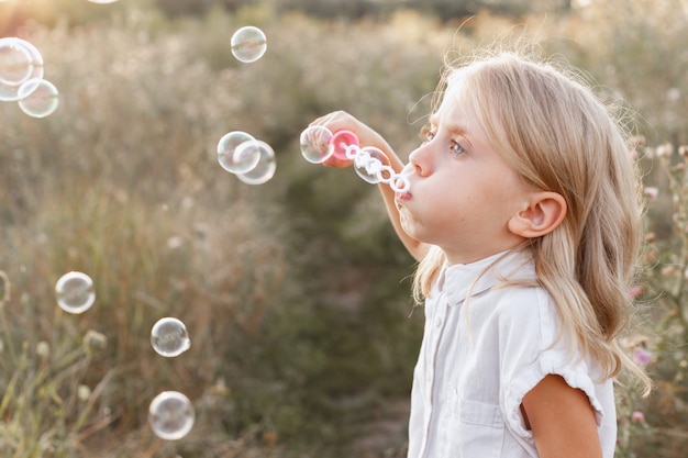 A little girl of 5 years old makes soap bubbles on a walk. sunny day