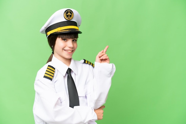 Little girl as a Airplane pilot over isolated chroma key background pointing finger to the side