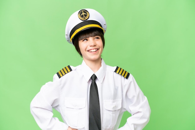 Little girl as a Airplane pilot over isolated chroma key background posing with arms at hip and smiling