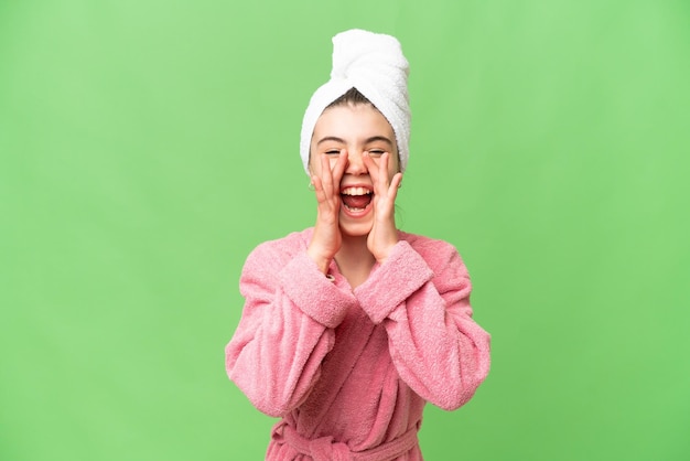 Little girl in a bathrobe over isolated chroma key background shouting and announcing something