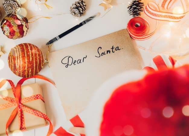 A little girl before Christmas writes a letter to Santa Claus on the table with garlands. child writes a letter to santa claus.