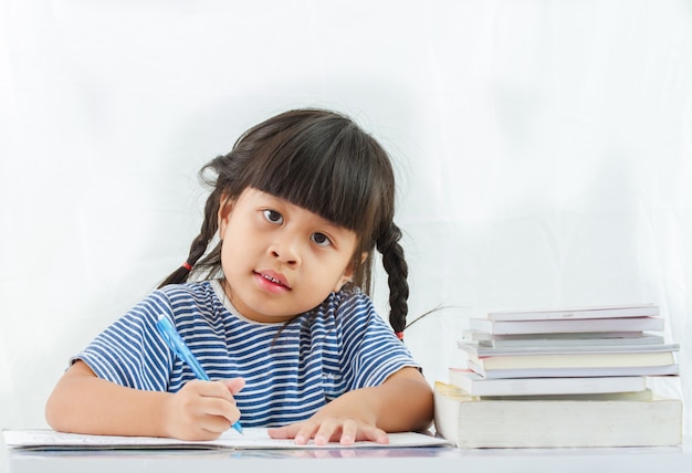 little girl being at a writing table with books isolated on white background.