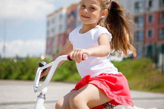 Little girl on a bicycle in summer park cycling outdoors