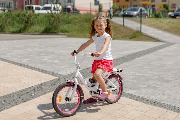 Little girl on a bicycle in summer park cycling outdoors