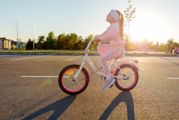 Little girl on a bicycle in summer park cycling outdoors