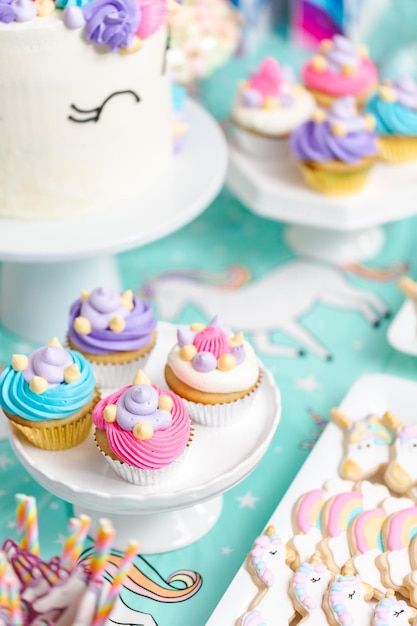 Little girl birthday party table with unicorn cake, cupcakes, and sugaer cookies.