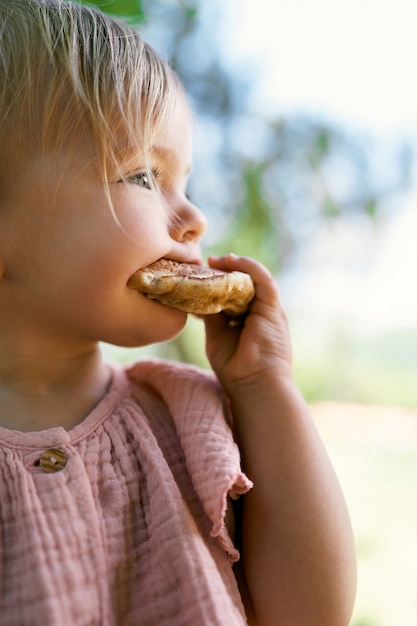 Little girl bits a pancake side view portrait