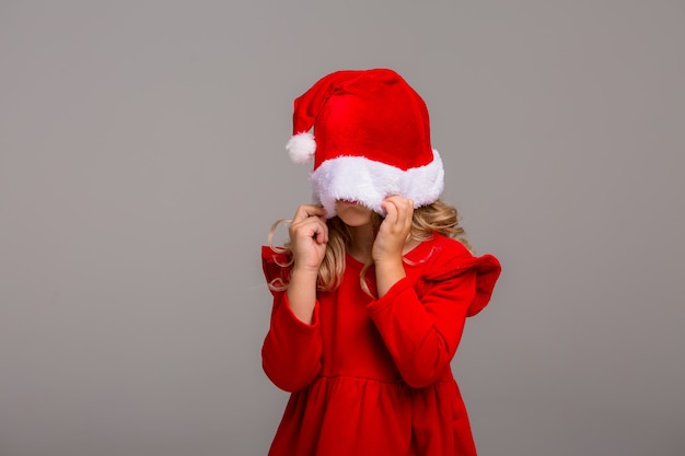 Little girl the blonde smiles in a Santa hat 