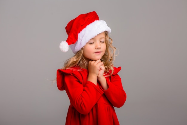 Little girl the blonde smiles in a Santa hat 