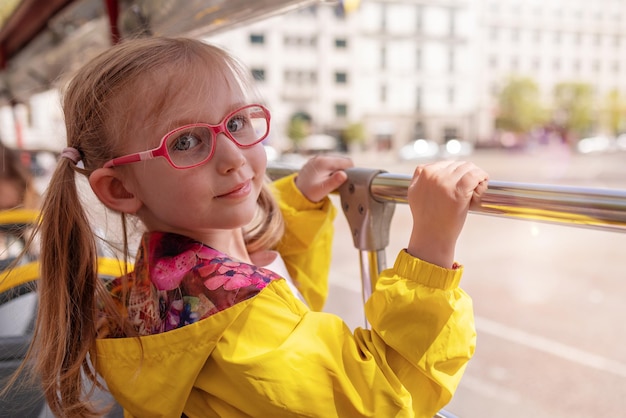 Little girl blonde with glasses The child rides in a tourist bus smiles