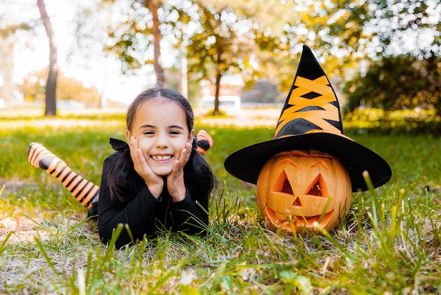 Little girl and boy carving pumpkin at Halloween. Dressed up children trick or treating. Kids trick or treat. Child in witch costume playing in autumn park. Toddler kid with jack-o-lantern.