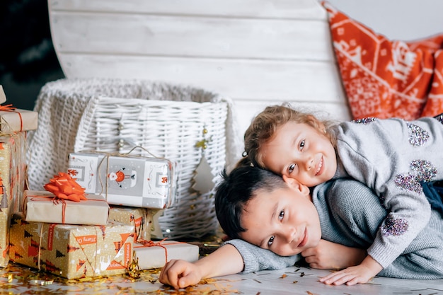 Little girl and boy sitting with christmas decoration and gifts