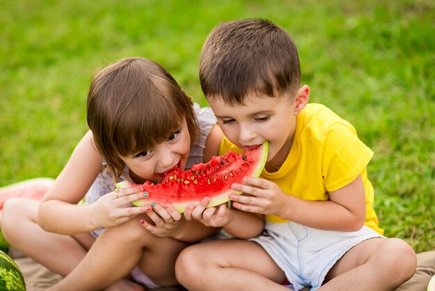 Little girl and boy with a piece of watermelon in hands