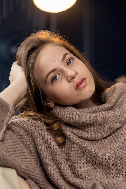 little girl in brown sweater Cute little girl in autumn clothes Portrait of a smiling little beautiful girl with long hair Girl 79 years old hands at the face