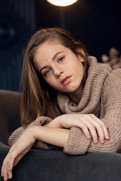 little girl in brown sweater Cute little girl in autumn clothes Portrait of a smiling little beautiful girl with long hair Girl 79 years old hands at the face