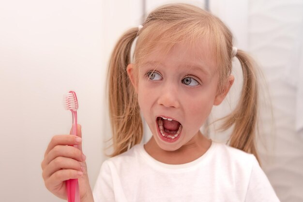 The little girl brushed her teeth and shows them with her mouth open In the hands of a toothbrush