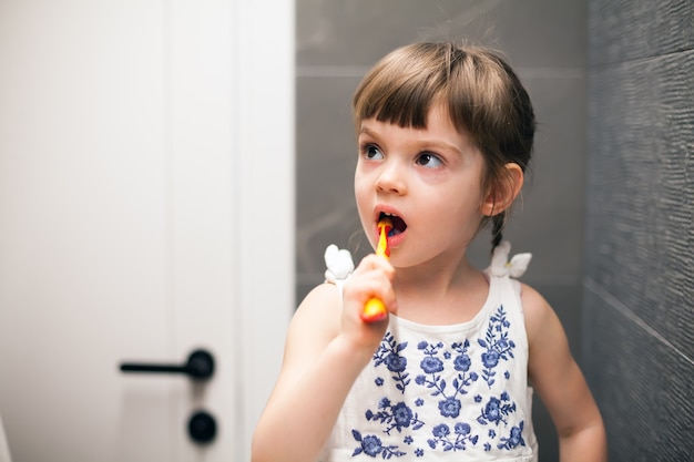 Little girl brushing her teeth in a bathroom