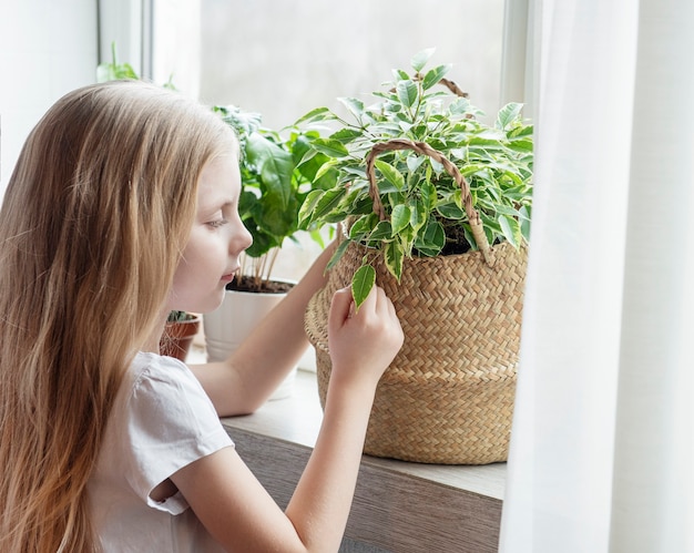 Little girl caring for house plants at home