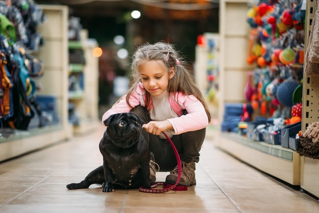 Little girl chooses house for puppy in pet shop