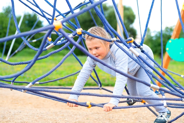 Little girl climbing in an adventure park. The girl loves to climb in the adventure of the rope course. Little girl on the rope obstacle course.