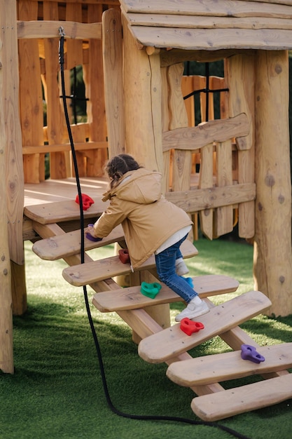 Little girl climbs up the hill on playground lot of enegry