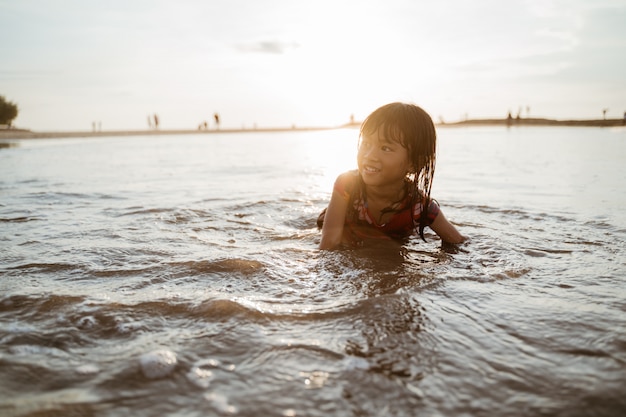 Little girl crawl on sand in the beach while playing with water