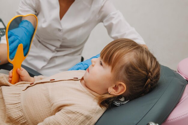 Little girl in the dentist's office, looks in the mirror and smiles. medicine and dentistry concept.