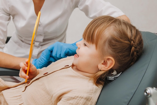 Little girl in the dentist's office, looks in the mirror and smiles. medicine and dentistry concept.