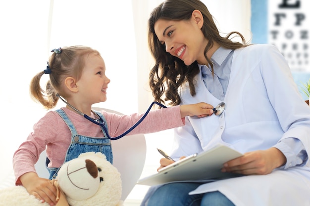 Little girl at the doctor for a checkup. Child auscultate the heartbeat of the doctor.