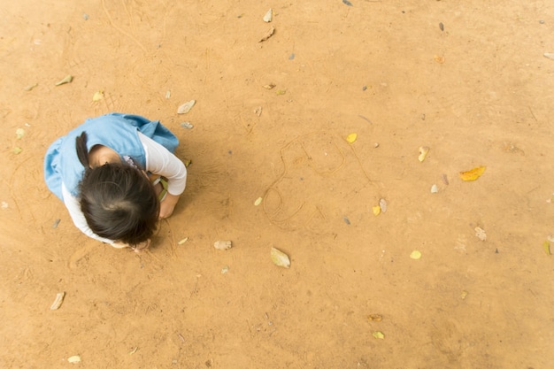 a little girl draw pictures on the ground. top view.