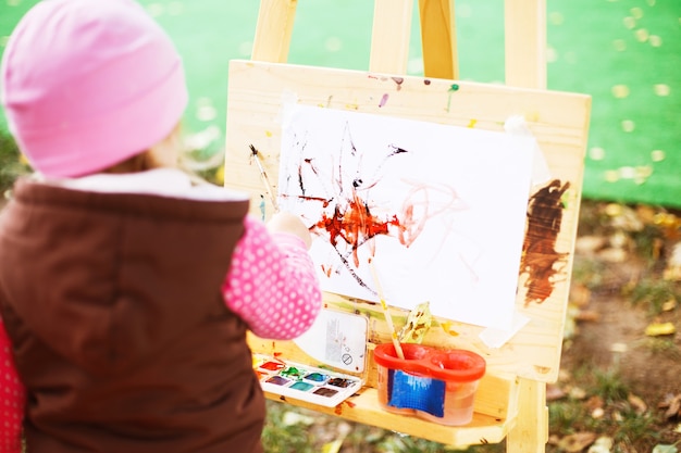 Little girl draws  on the easel