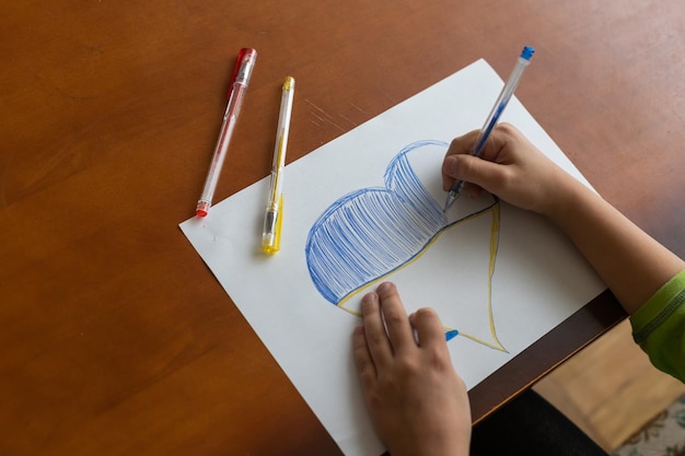 A little girl draws a heart. Top view. Copy space for text