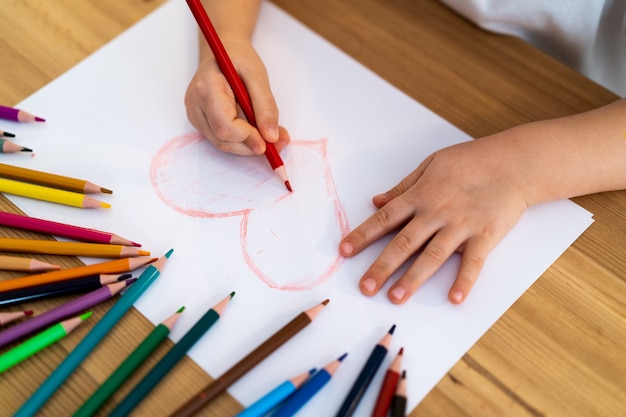 Little girl draws a red heart